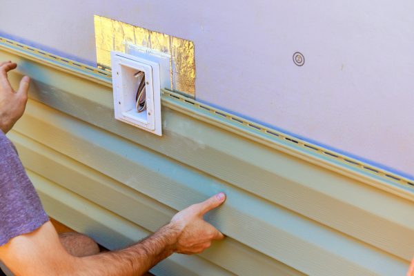Vinyl plastic siding panels are installed on wall facade of new building by an employee
